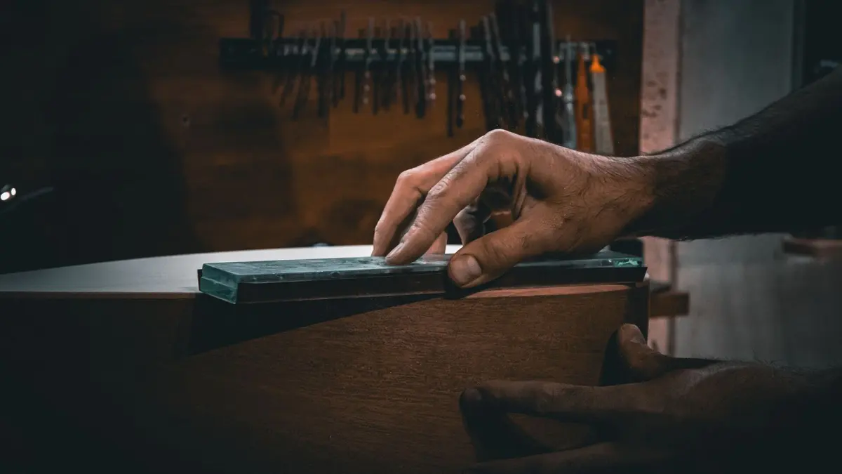 Ciseaux à bois posés près d'une pierre à aiguiser, atelier de menuisier, lumière douce